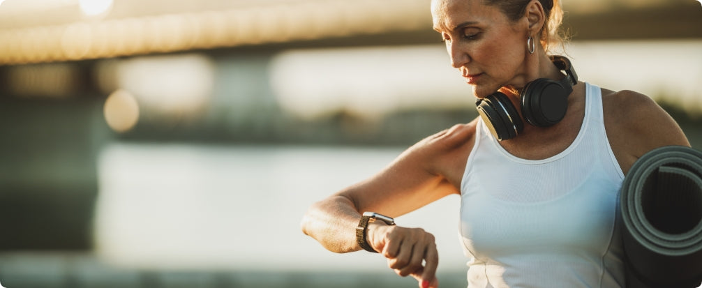 woman with workout gear and headphones looking at her watch